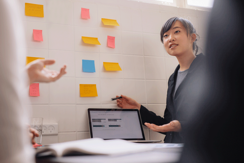 A designer in front of a wall of Post-It notes