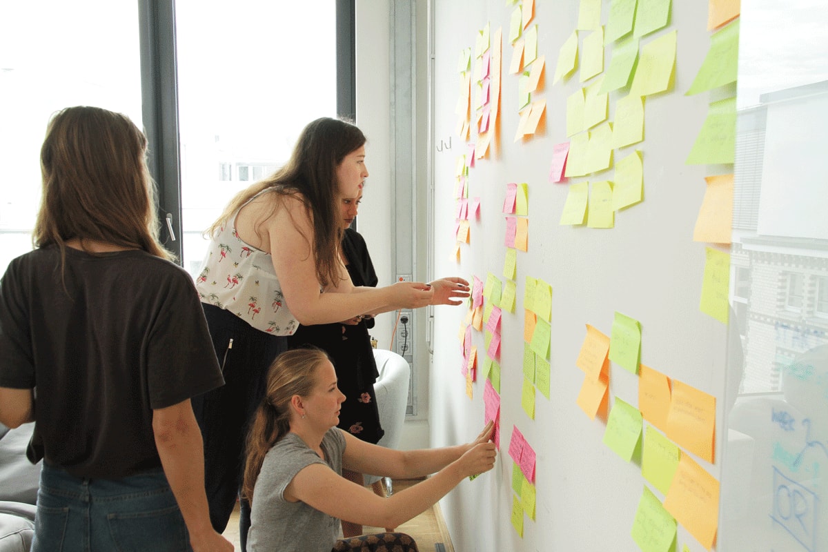 A group of colleagues sticking Post-its on a wall as part of a design thinking workshop